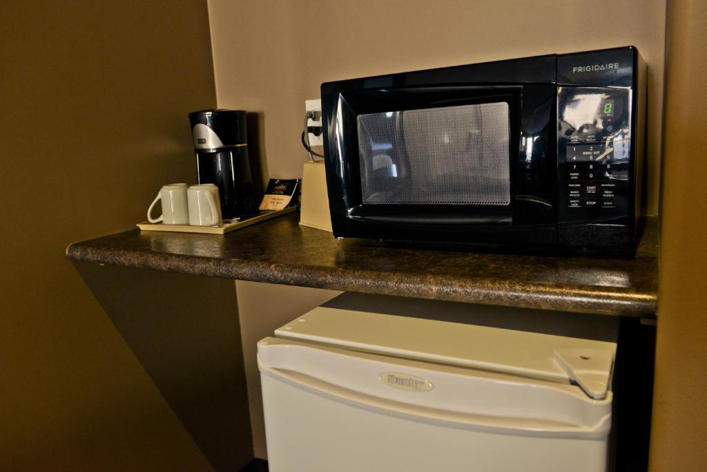 a microwave sitting on top of a counter over a refrigerator at 121 Steakhouse & Motel in Assiniboia