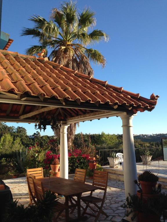 a wooden pergola with a wooden table and chairs at Wavin' Trees Ericeira in Ericeira