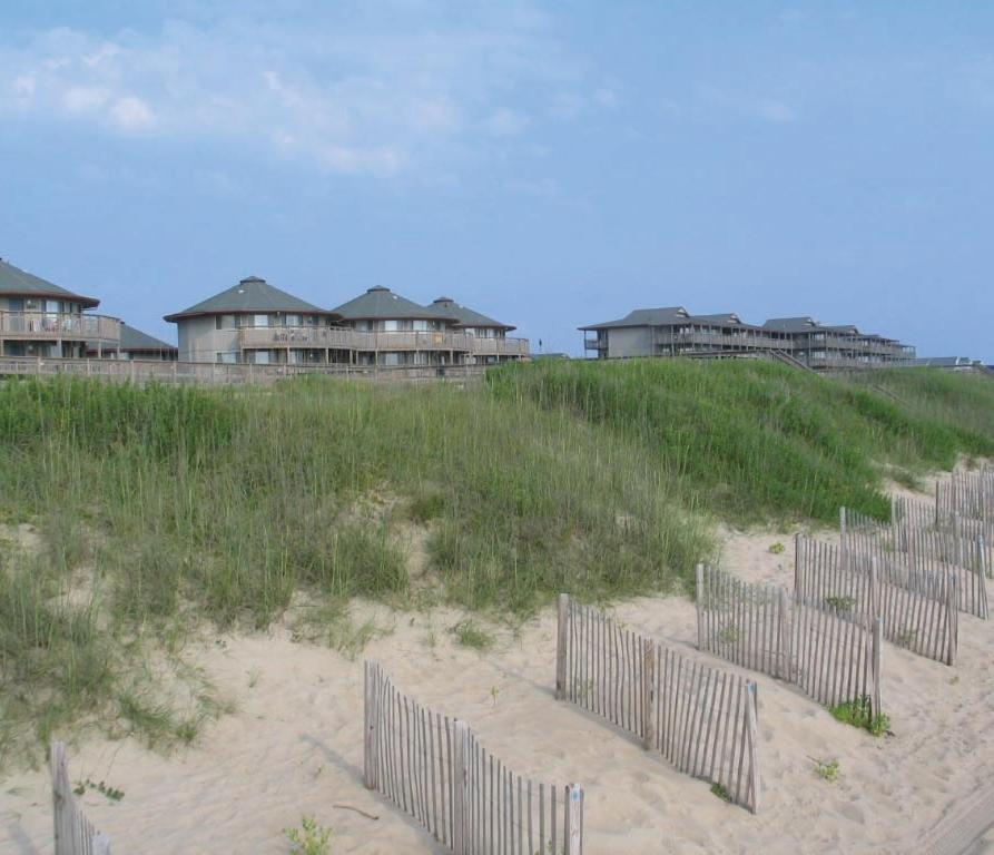a row of fences on a sandy beach with houses at Outer Banks Beach Club II Resorts in Kill Devil Hills