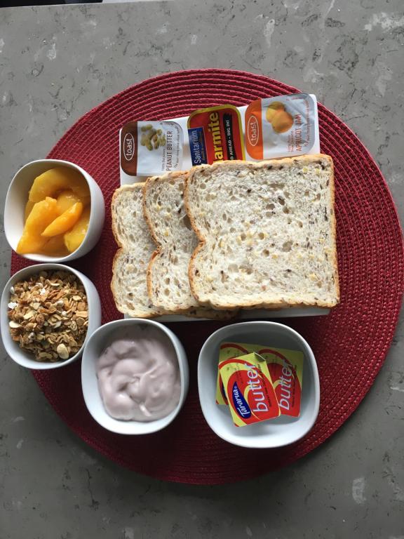ein Teller mit Brot, Joghurt und anderen Snacks in der Unterkunft Pedlars Motel in Paeroa
