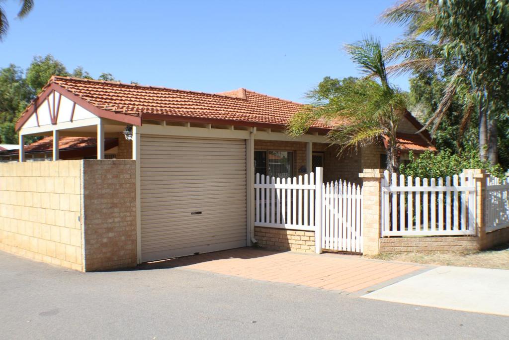 une maison avec une clôture blanche et un garage dans l'établissement Geraldton Luxury Retreat 2 with free Streaming, à Geraldton
