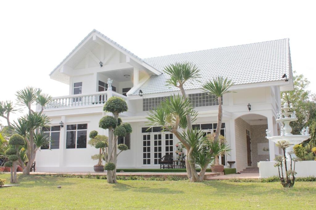 a white house with palm trees in front of it at HOME@HOSTEL KANCHANABURI in Kanchanaburi