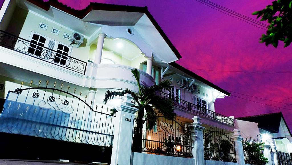 a white house with a palm tree in front of it at City Stay Homestay Jogja in Yogyakarta