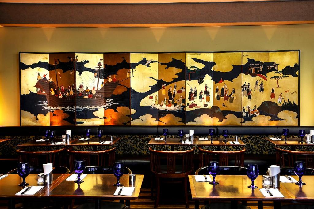 a restaurant with tables and a large painting on the wall at New Otani Inn Tokyo in Tokyo