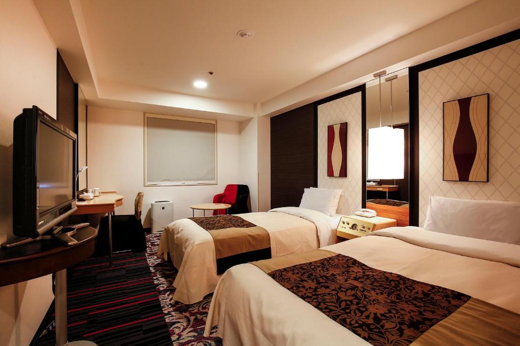 a hotel room with two beds and a flat screen tv at New Otani Inn Tokyo in Tokyo