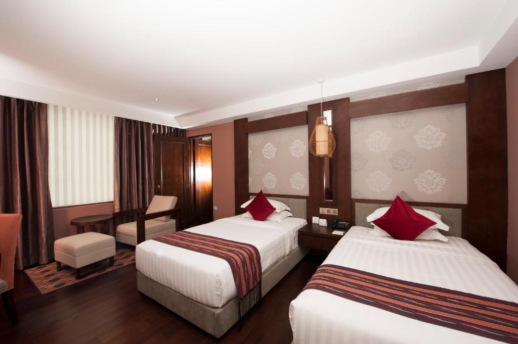 a hotel room with two beds and a desk at Rose Garden Hotel in Yangon