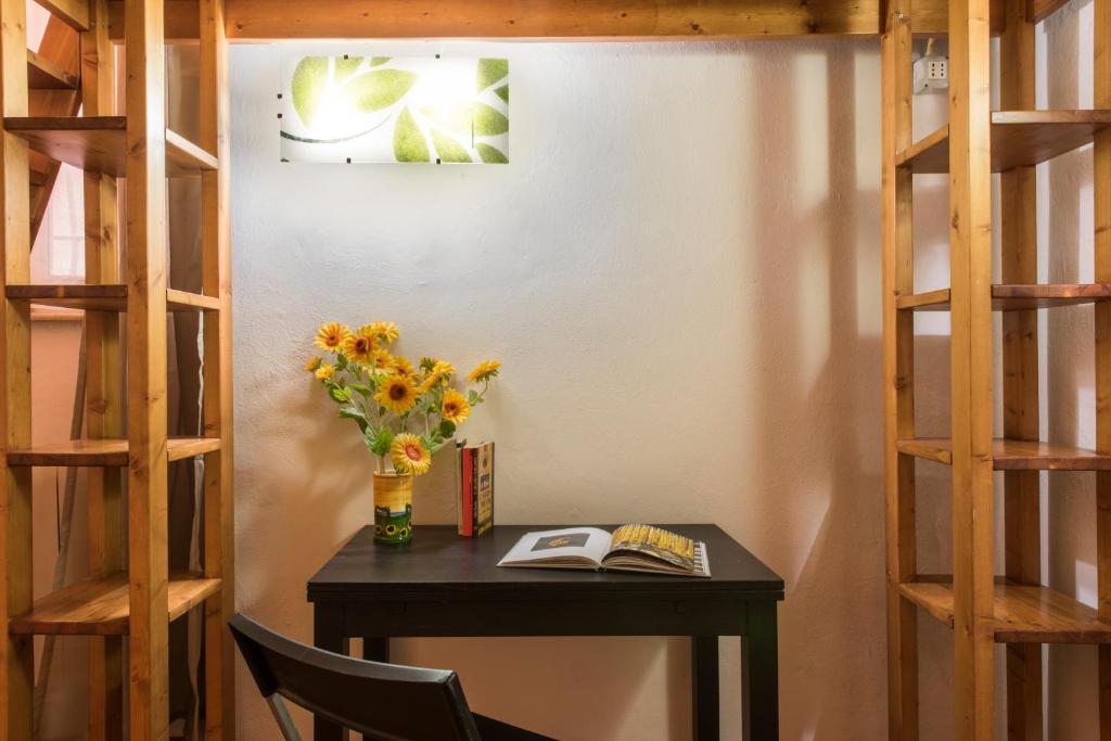 een bureau met een vaas met bloemen en een boek bij Casa Raffaella in Pisa