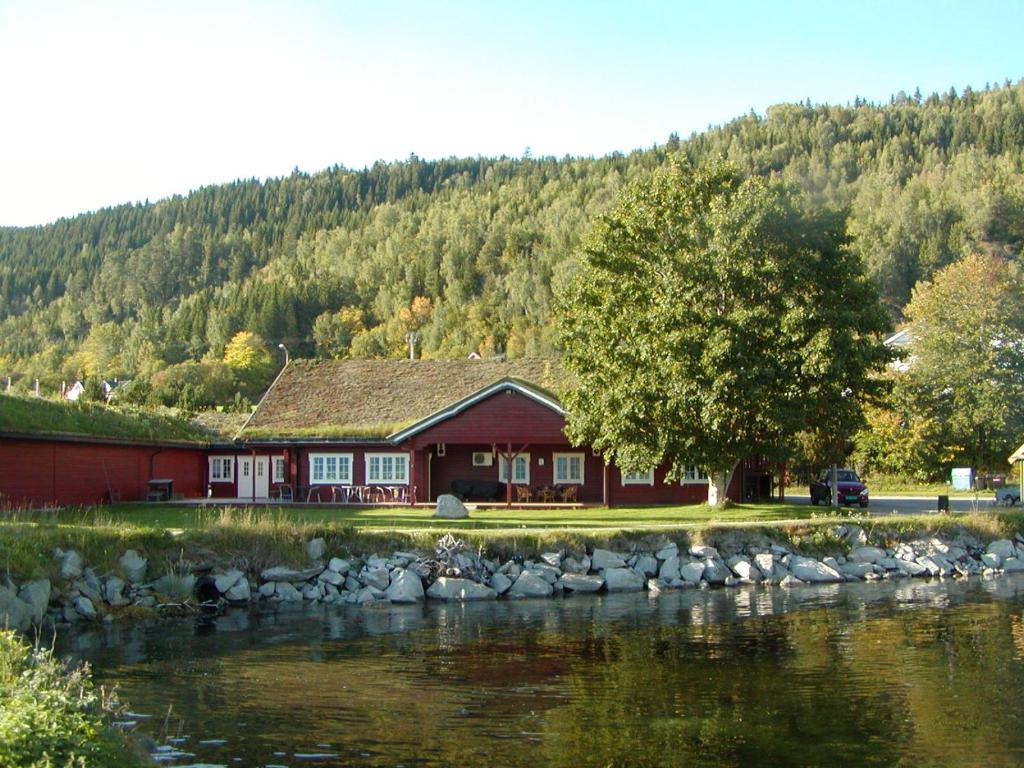 a red house next to a river with a tree at Jækta Fjordstue in Mosvik