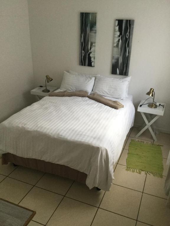 een slaapkamer met een bed met witte lakens en een groen tapijt bij Self-catering Studio, Unit 3 on Krupp in Windhoek