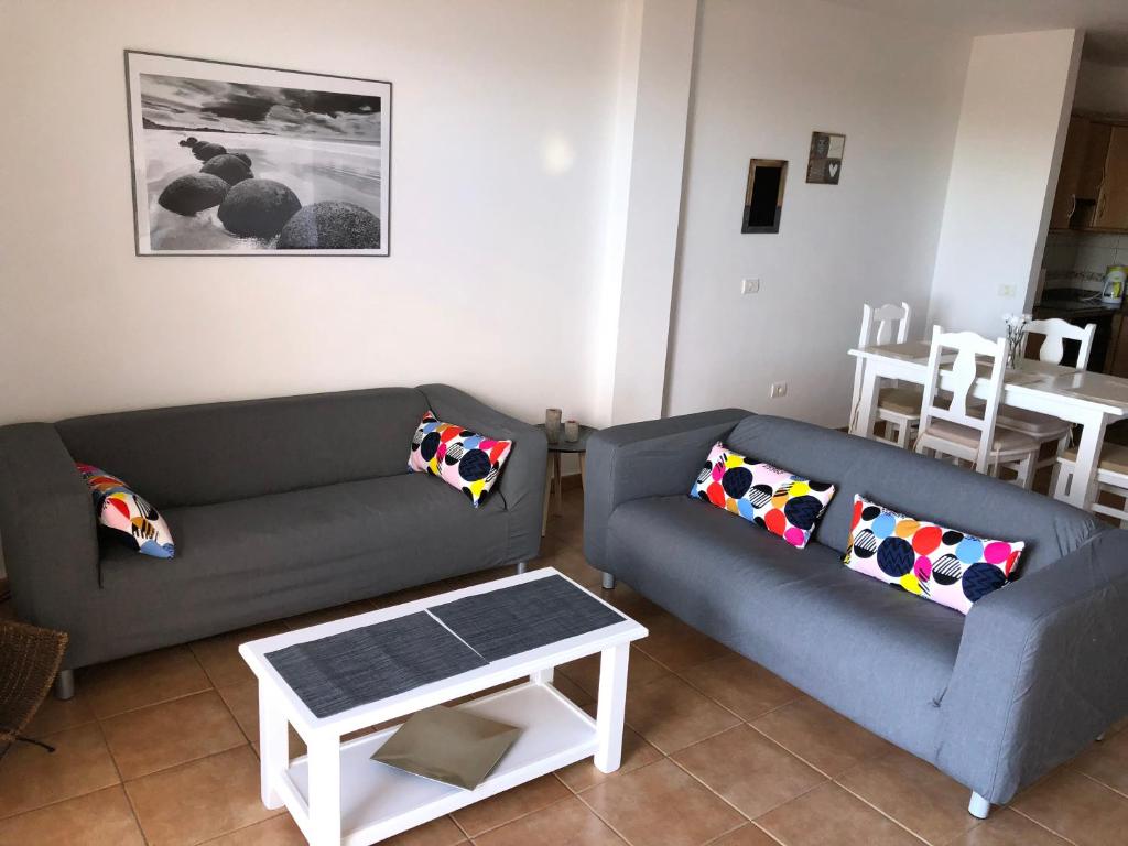 ein Wohnzimmer mit einem Sofa und einem Tisch in der Unterkunft Apartamentos Ajabo Adeje in Adeje