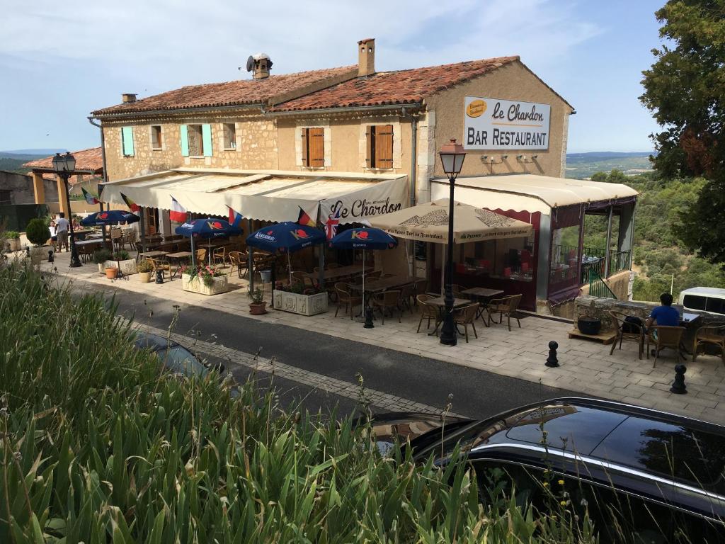 a building with tables and umbrellas on a street at Le Chardon 1 in Baudinard