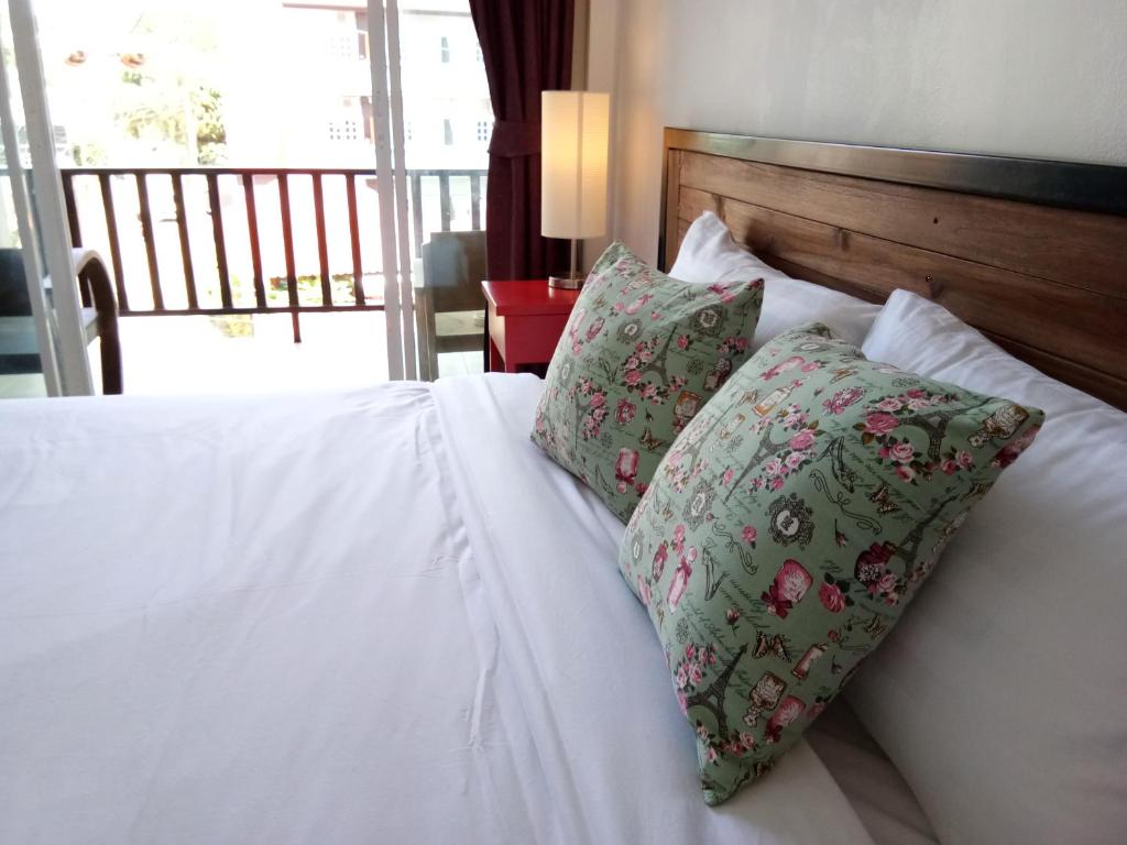 a white bed with two pillows on it with a window at The Wang in Chalong 