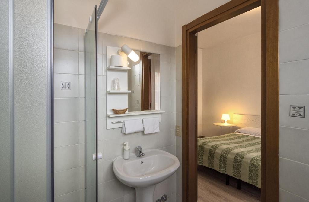 uma casa de banho com um lavatório e um chuveiro com uma cama em Hotel Cecile em Pisa