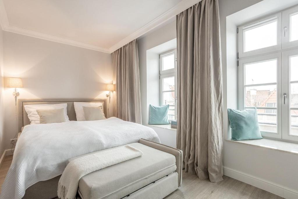 a white bedroom with a bed and two windows at VIU Spirit of Gdansk in Gdańsk