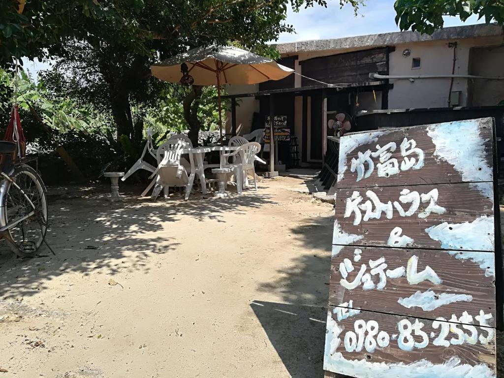 a sign in front of a table and an umbrella at Taketomijima Guesthouse and je Taime in Taketomi