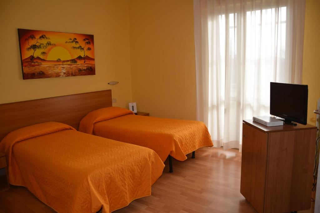 a hotel room with two beds and a flat screen tv at Piccolo Hotel in Rosignano Solvay
