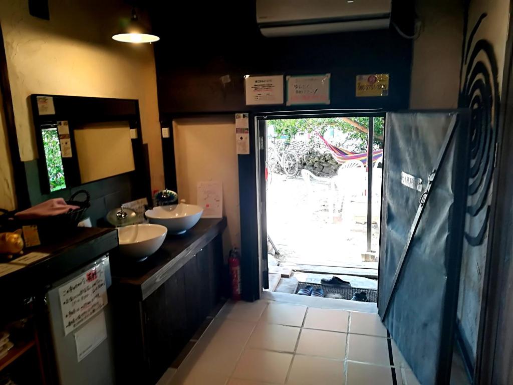 a bathroom with two sinks and a sliding glass door at Taketomijima Guesthouse and je Taime in Taketomi