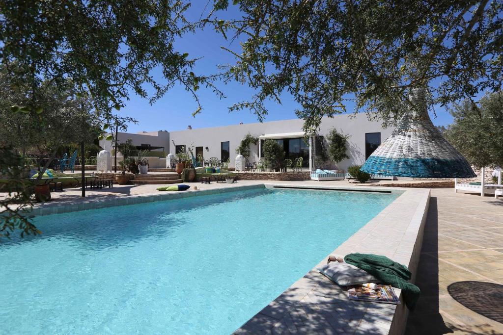 a swimming pool with a person laying next to it at Les Jardins de Villa Maroc in Essaouira
