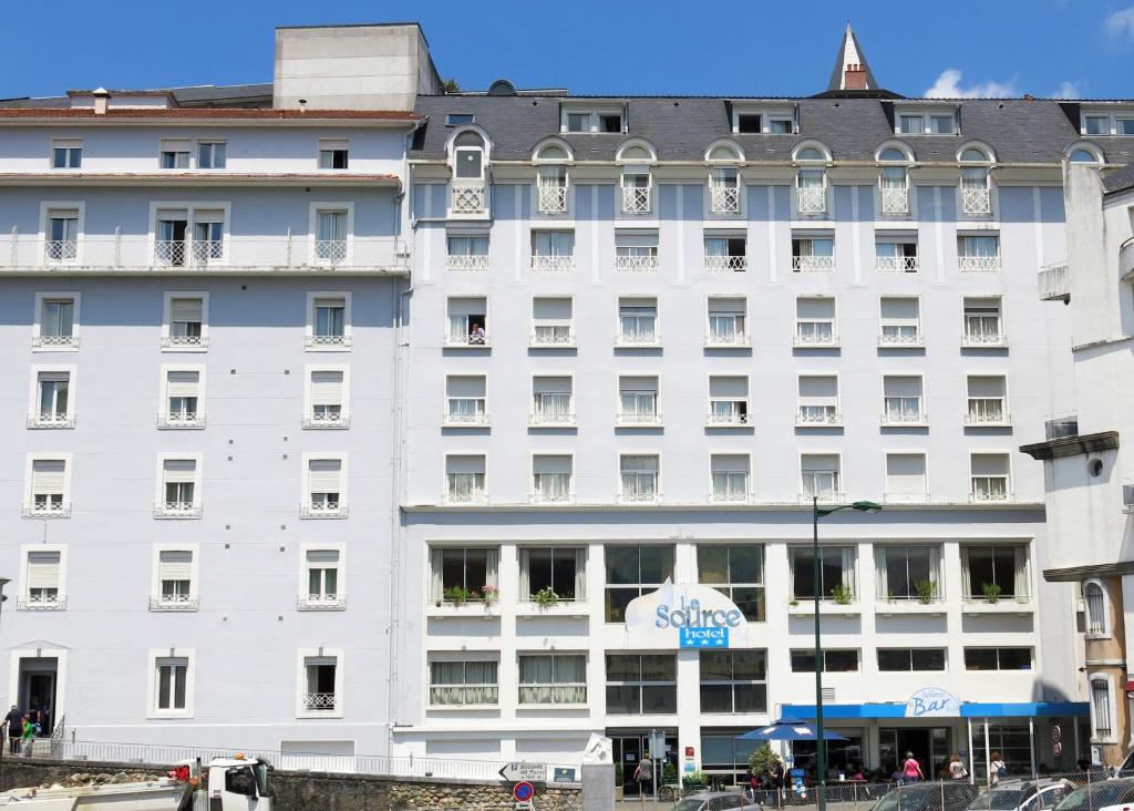 a large white building with a sign on it at Hôtel La Source in Lourdes