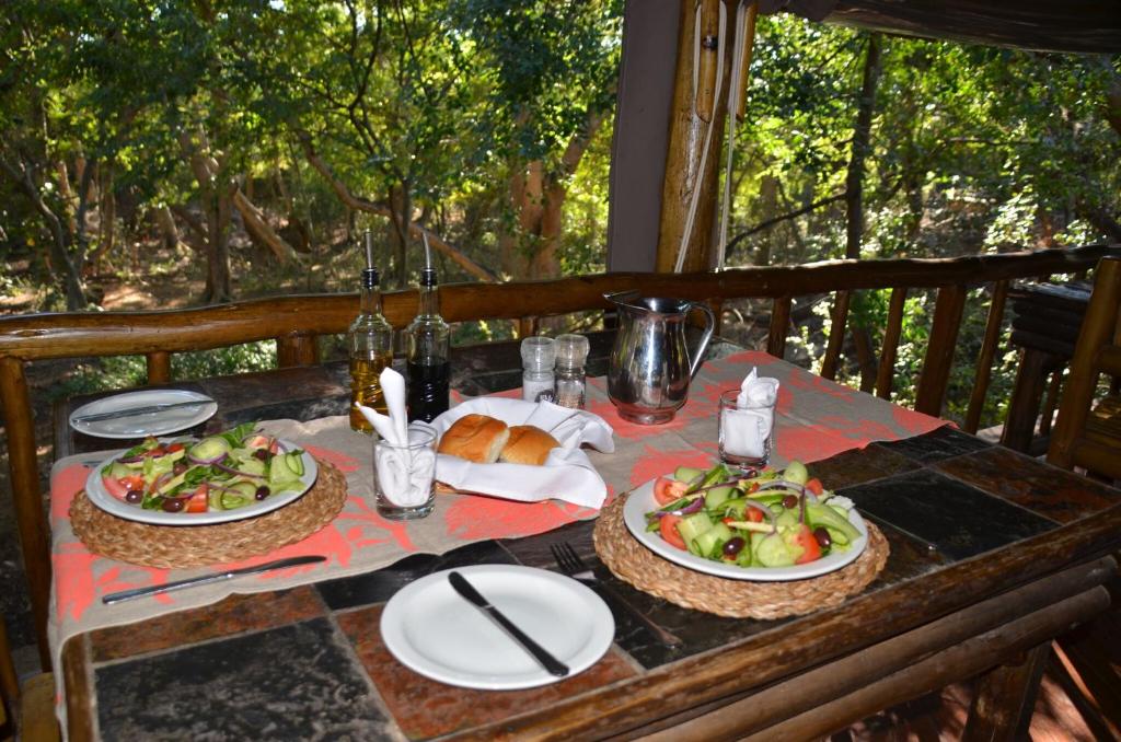 a table with two plates of food on it at Moholoholo Forest Camp in Hoedspruit
