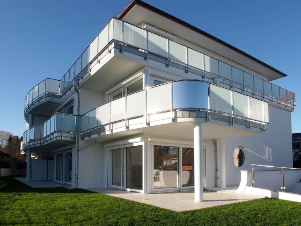 een wit huis met een balkon en een gazon bij Ferienwohnung Timmendorfer in Timmendorfer Strand