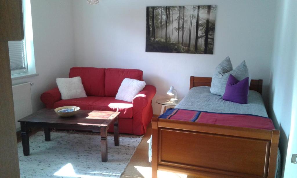 ein Schlafzimmer mit einem roten Sofa und einem roten Stuhl in der Unterkunft Chez nous in Pfronten