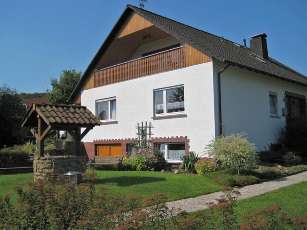 a white house with a wooden roof and a yard at Quiet apartment in Merlsheim with balcony in Nieheim