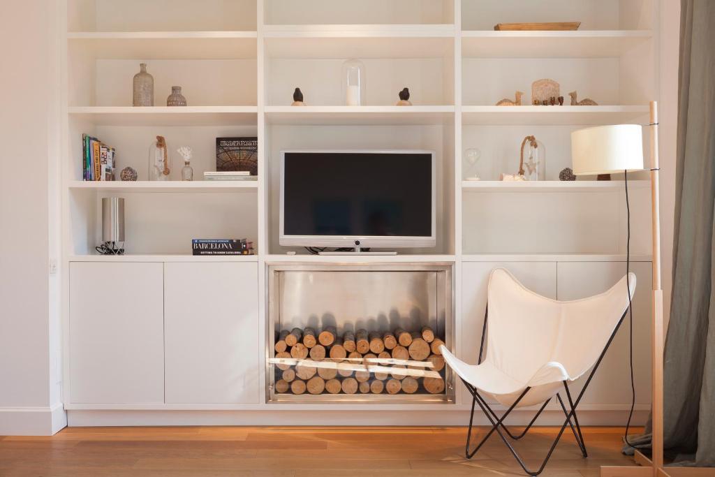 a living room with a fireplace and a white chair at Click&Flat Luxury Sant Joan in Barcelona