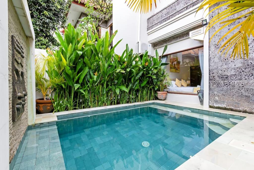 a pool in the backyard of a house with plants at Villa Tiah in Kuta