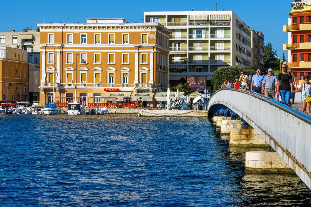 people walking over a bridge over a river with buildings at Summertime Apartments in Zadar