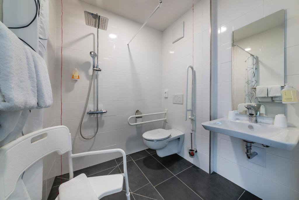 a white bathroom with a toilet and a sink at Hostel Art &amp; Style in Singen