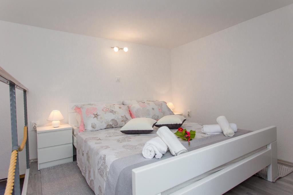 a white bedroom with a bed with towels on it at Studio Apartment Vasilj in Split