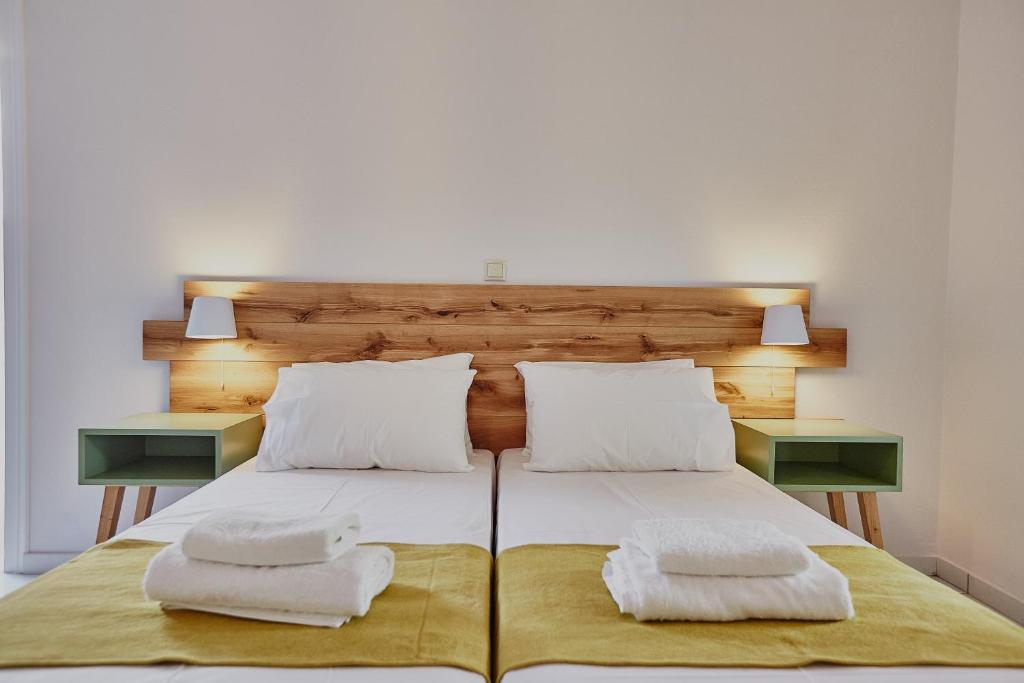a bed with two white pillows and two night stands at Irene Studios in ayios Petros