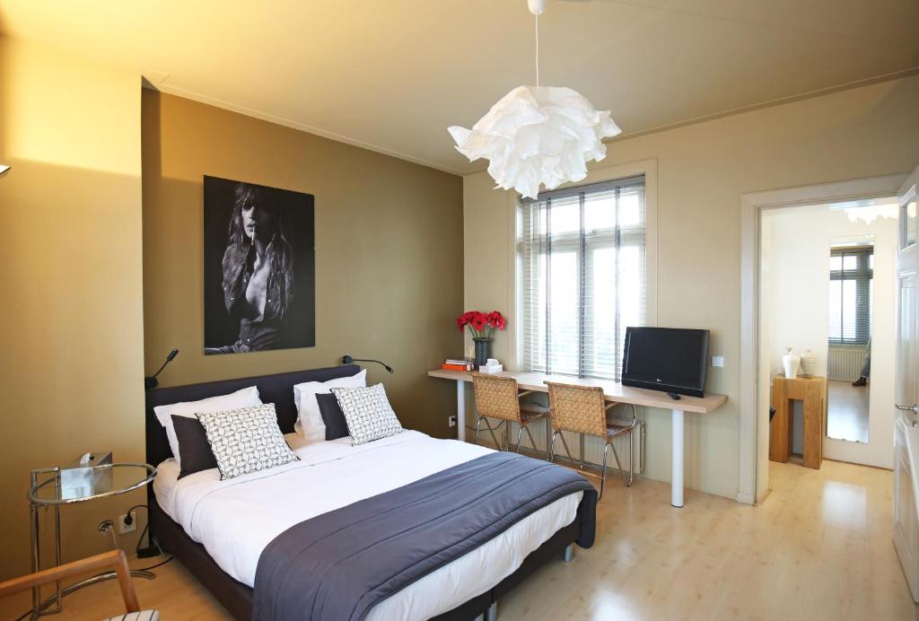 a bedroom with a large bed and a chandelier at Canal Studio Apartment in Amsterdam