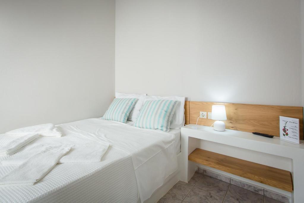 a white bedroom with a white bed and a nightstand at Irene Studios in Agios Petros