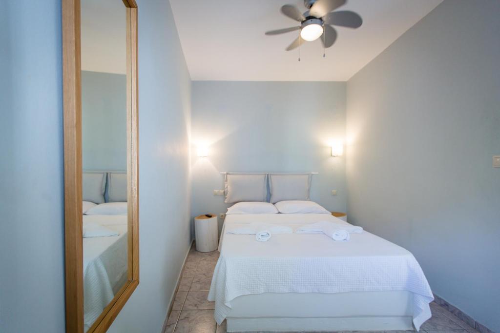a bedroom with a white bed and a mirror at Irene Studios in Agios Petros