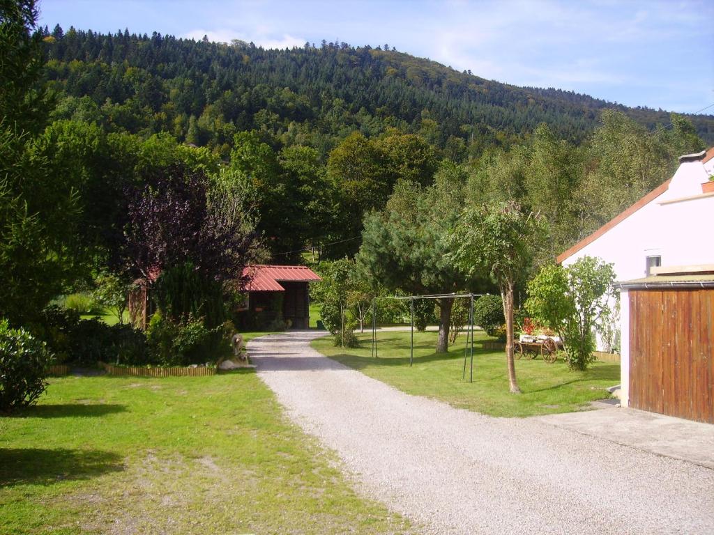una strada sterrata accanto a una casa e a una montagna di Gîtes Les Grandes Voies - Clé Vacances a Le Ménil