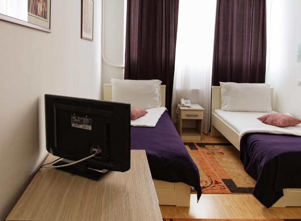 una camera con due letti e un monitor per computer su un tavolo di Garni Hotel Hamburg a Zaječar