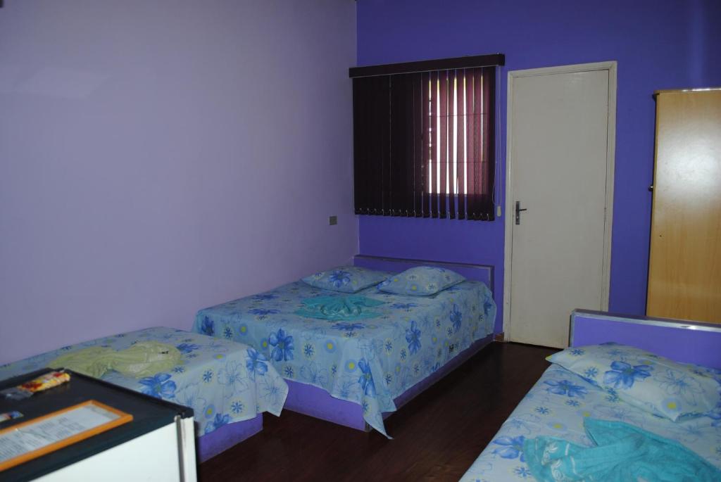 two beds in a room with purple walls at Hotel Principe in Barra Bonita
