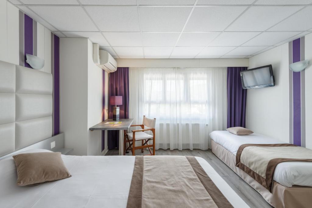 a hotel room with two beds and a desk at Logis Hotel Le Sablier du Temps in Argentat