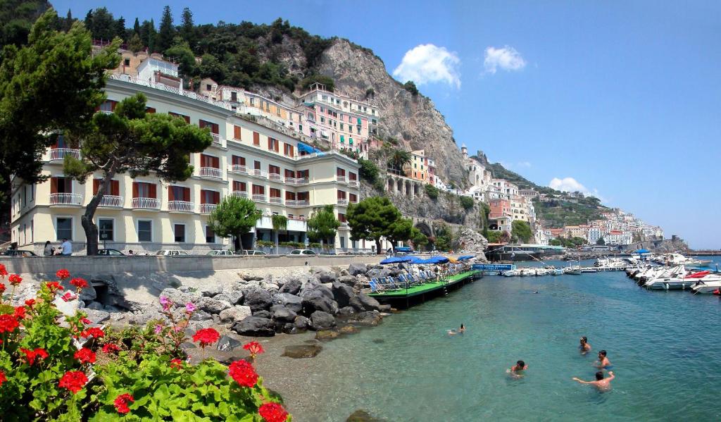 a group of people swimming in a river with buildings at Hotel La Bussola in Amalfi