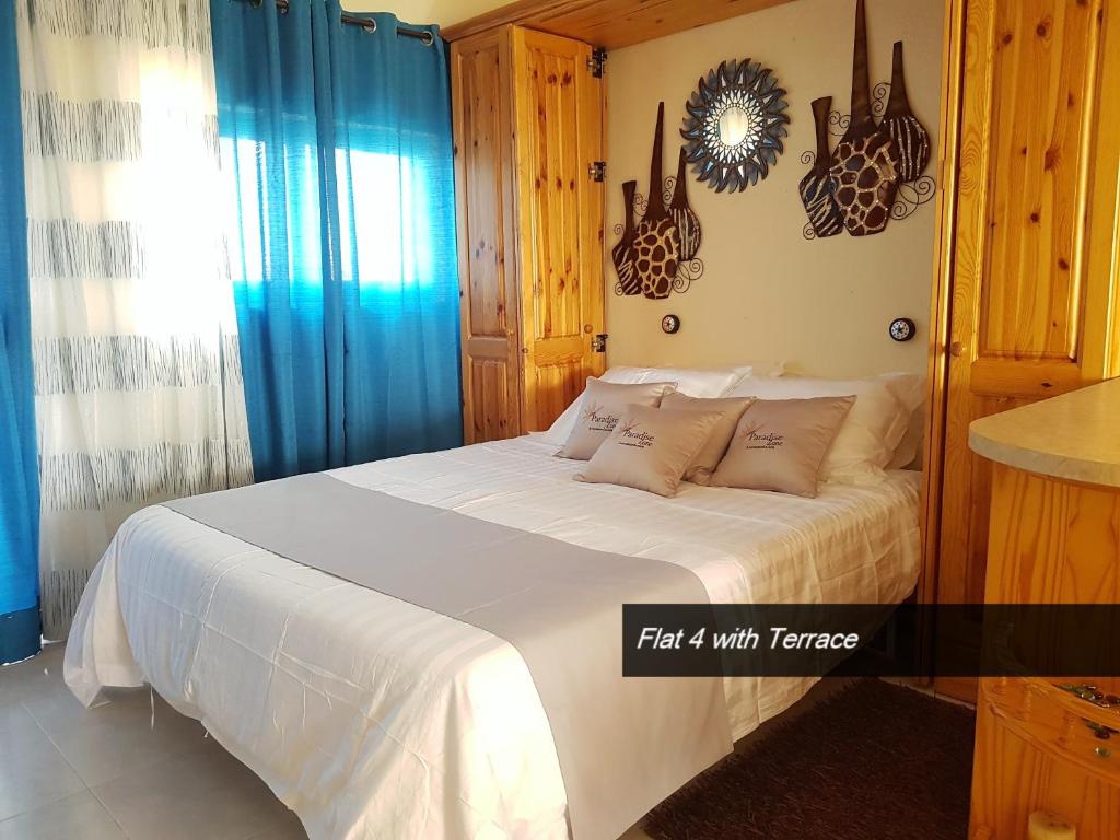 a bedroom with a white bed with blue curtains at Pretty Bay Apartments in Birżebbuġa