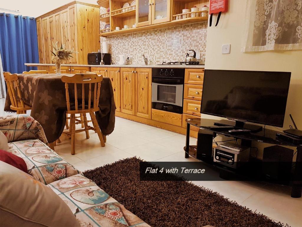 a living room with a couch and a tv and a kitchen at Pretty Bay Apartments in Birżebbuġa