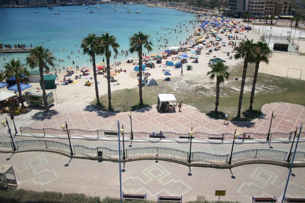 a beach with a bunch of people in the water at Pretty Bay Apartments in Birżebbuġa