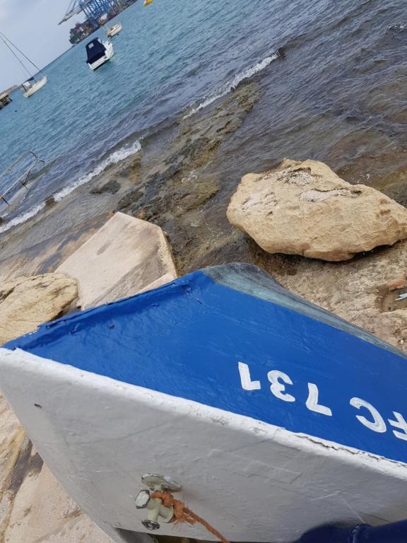 a blue and white boat sitting on the beach at Pretty Bay Apartments in Birżebbuġa