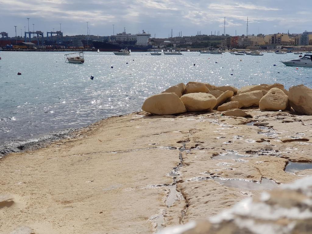 a beach with a body of water with boats in it at Pretty Bay Apartments in Birżebbuġa