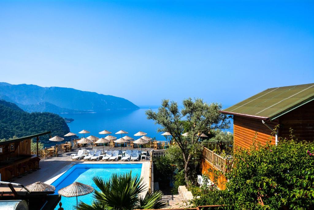 a resort with a swimming pool with umbrellas and chairs at Kabak Armes Hotel in Faralya