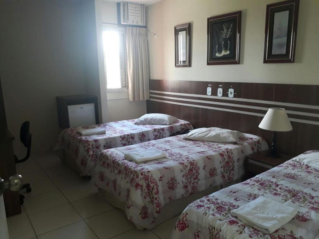 a hotel room with two beds and a window at San Marino Hotel in São José dos Campos