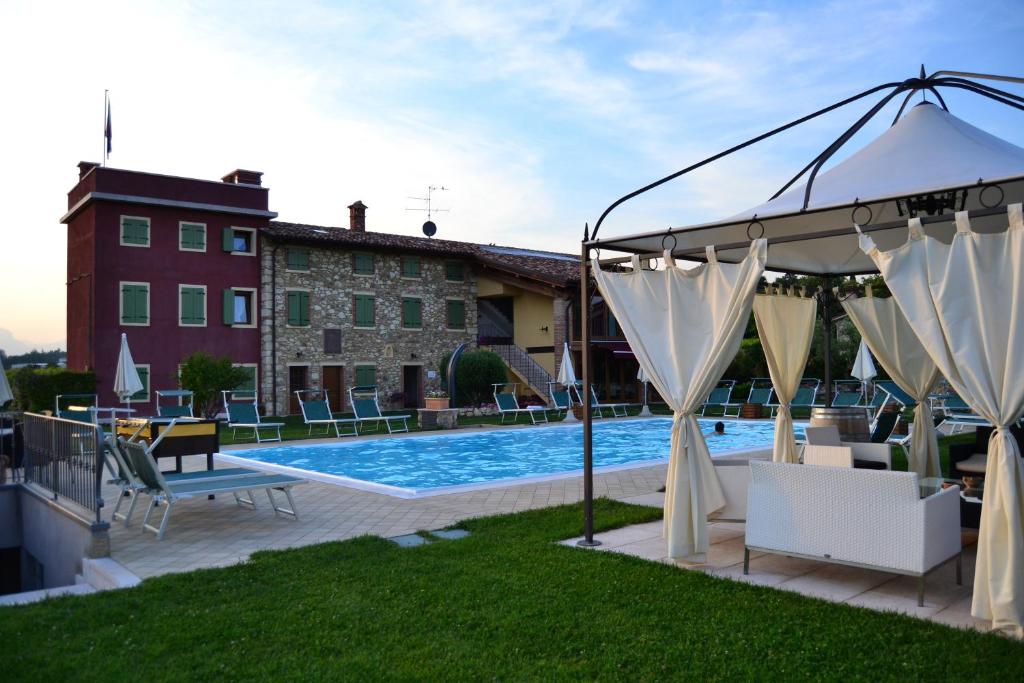 a pool with a gazebo next to a building at Agriturismo Le Campagnole in Bardolino