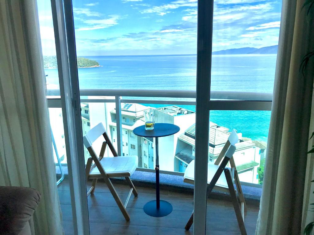 d'un balcon avec une table et des chaises donnant sur l'océan. dans l'établissement Porto Real Suites Apto Luxo com vista p/ Mar, à Mangaratiba